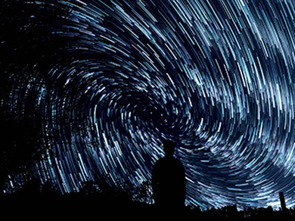 Photo Credit, Jeremy Thomas, a black silhouette of person looking at gyre of stars